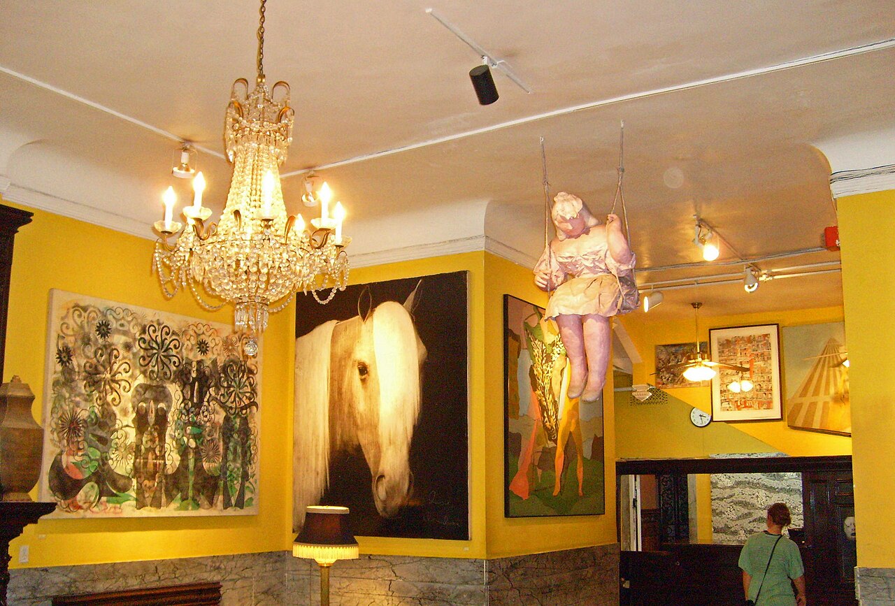 The lobby of the Hotel Chelsea with artwork on the walls and a chandelier