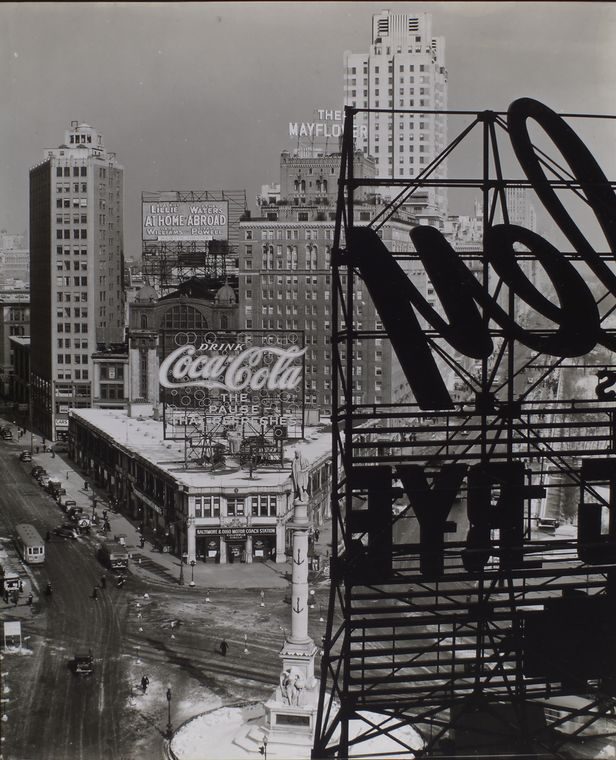 Black and white view of Columbus Circle in 1938 with the Columbus monument, rooftop signs and a Coca-Cola advertisement