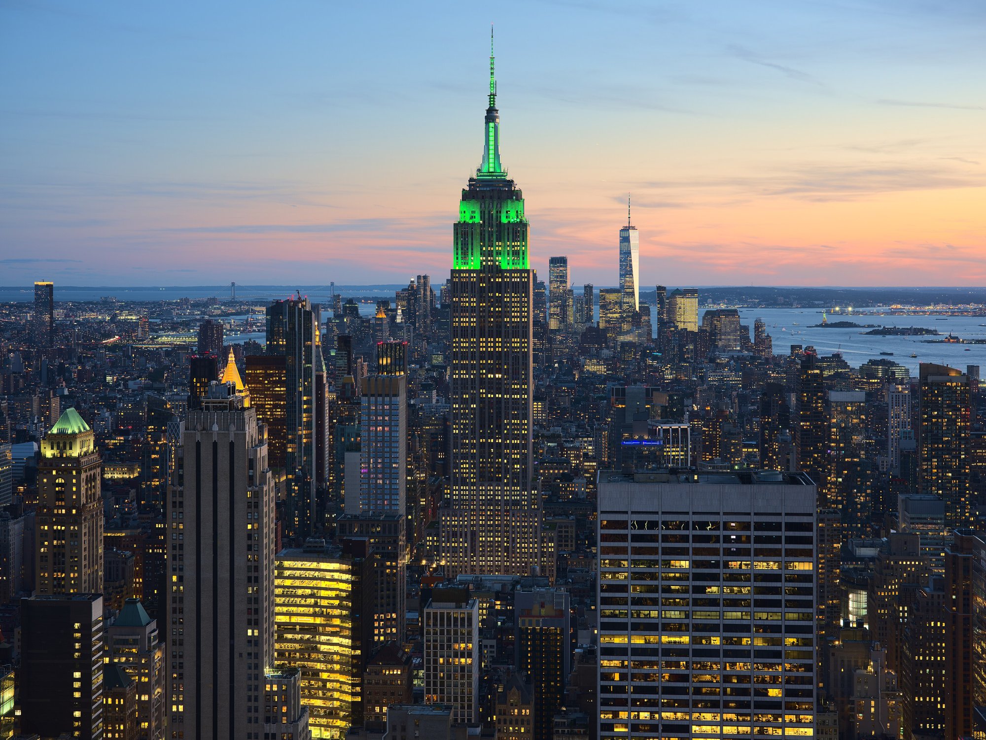 The Empire State Building lit green at dusk above Midtown Manhattan in 2021.