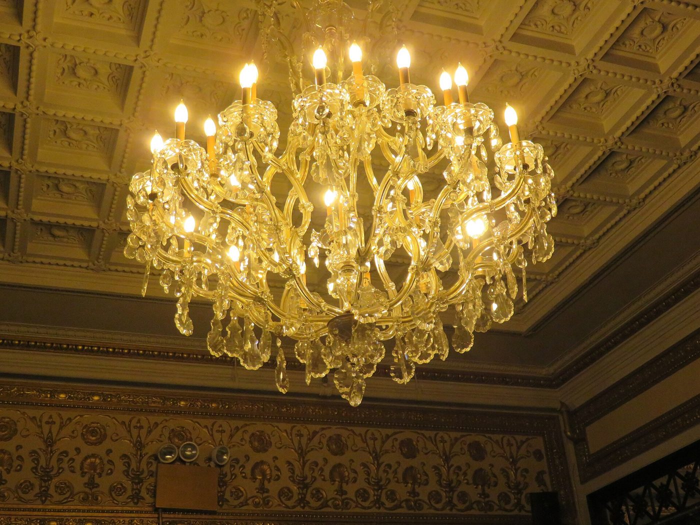 A crystal chandelier hanging from the coffered ceiling in the lobby of the Hudson Theatre in Manhattan, 2017