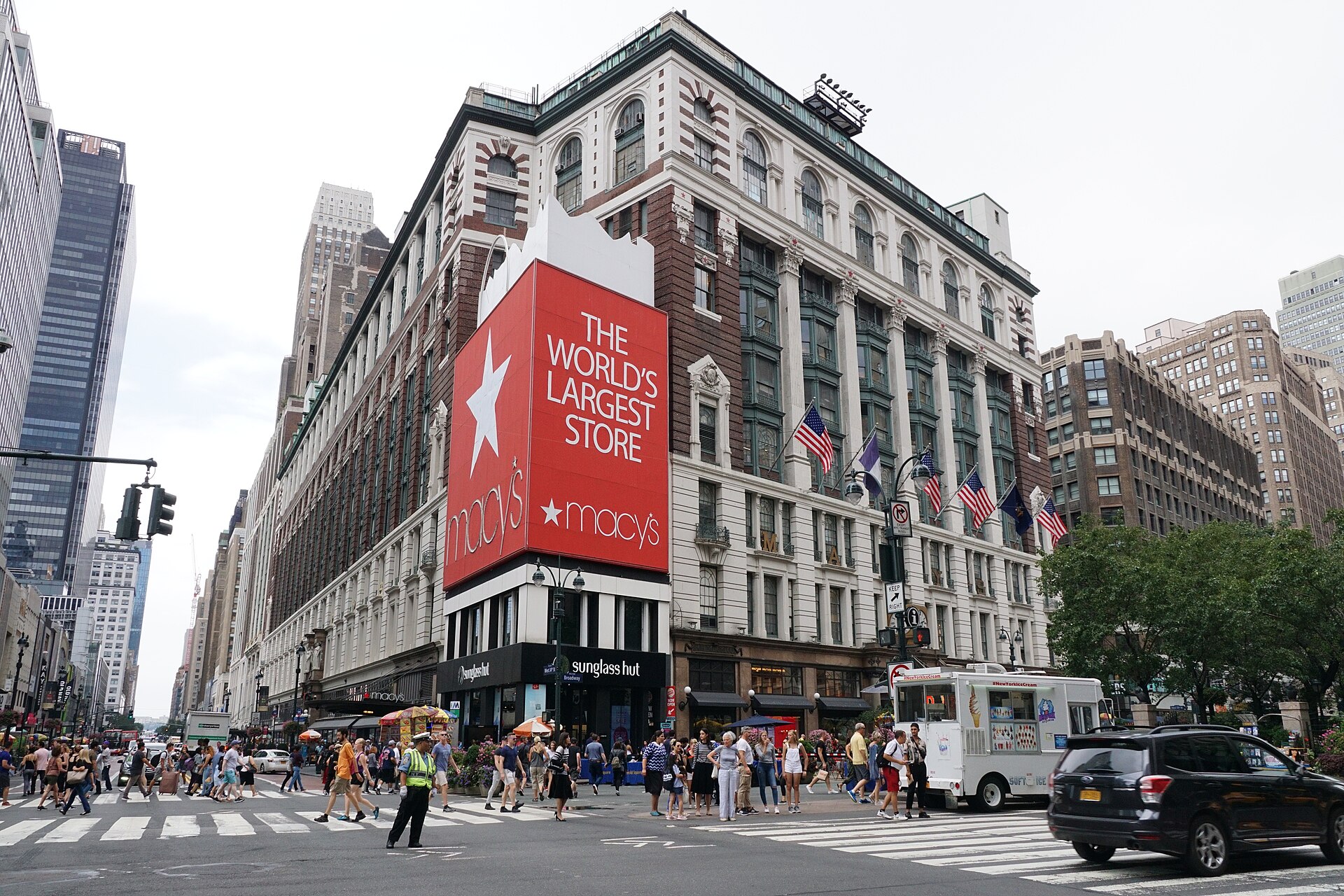 The Broadway front of Macy's in 2018, with the giant red shopping-bag sign reading THE WORLD'S LARGEST STORE on the small corner building