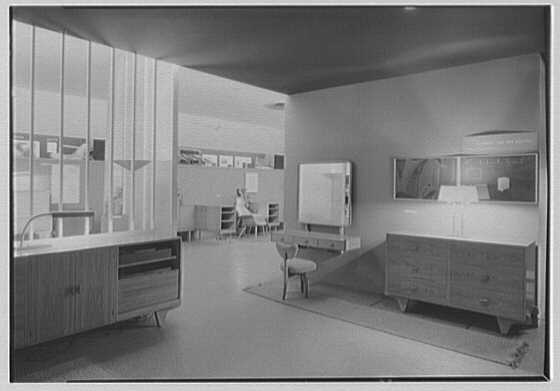A black and white photograph of a modern room display with a dresser, a chair and a glass wall inside the Museum of Modern Art in 1941
