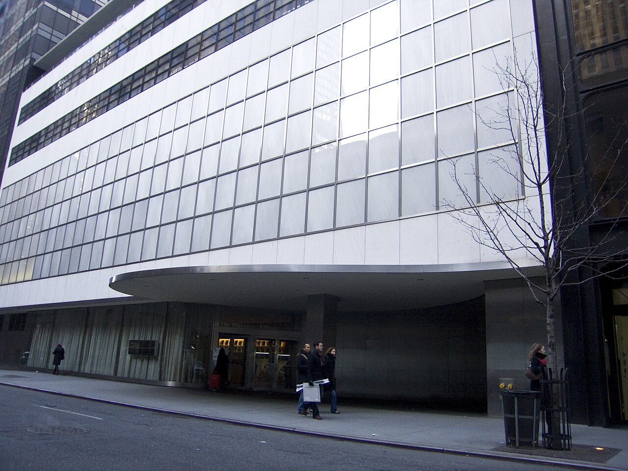 The curved canopy and metal and glass facade of the Museum of Modern Art at street level on West 53rd Street