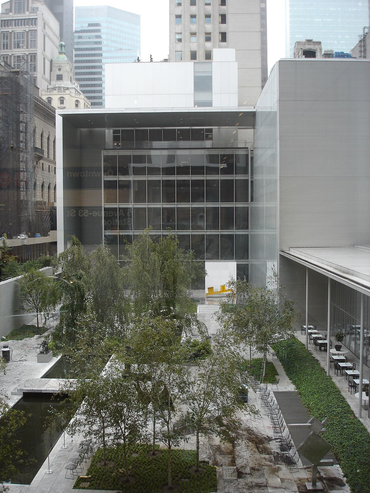 The Abby Aldrich Rockefeller Sculpture Garden at the Museum of Modern Art, with trees, a long pool and the museum building behind