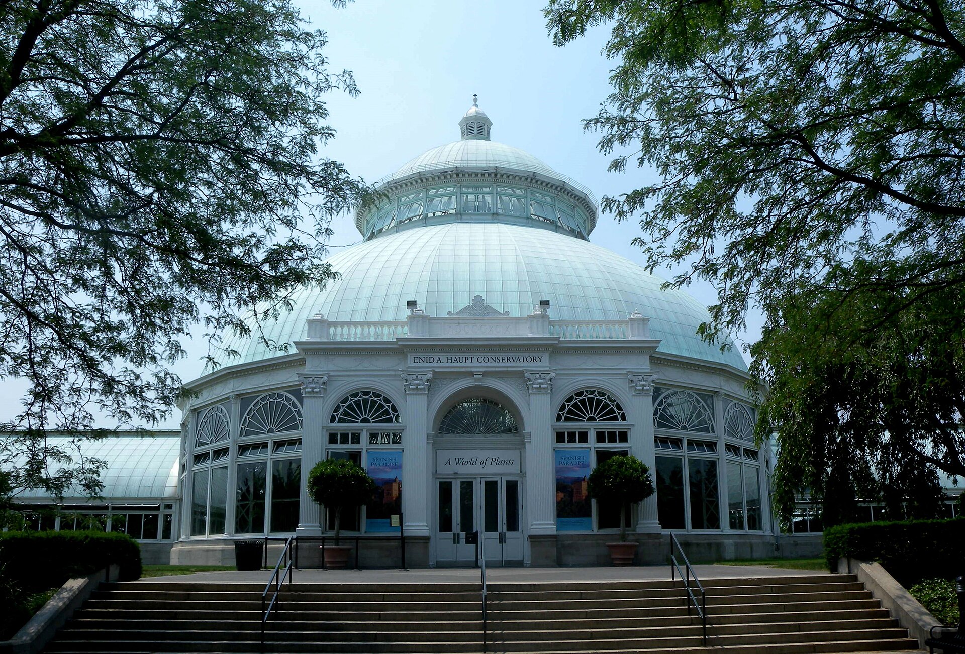 The Enid A. Haupt Conservatory, a white Victorian glasshouse with a large central dome, framed by trees