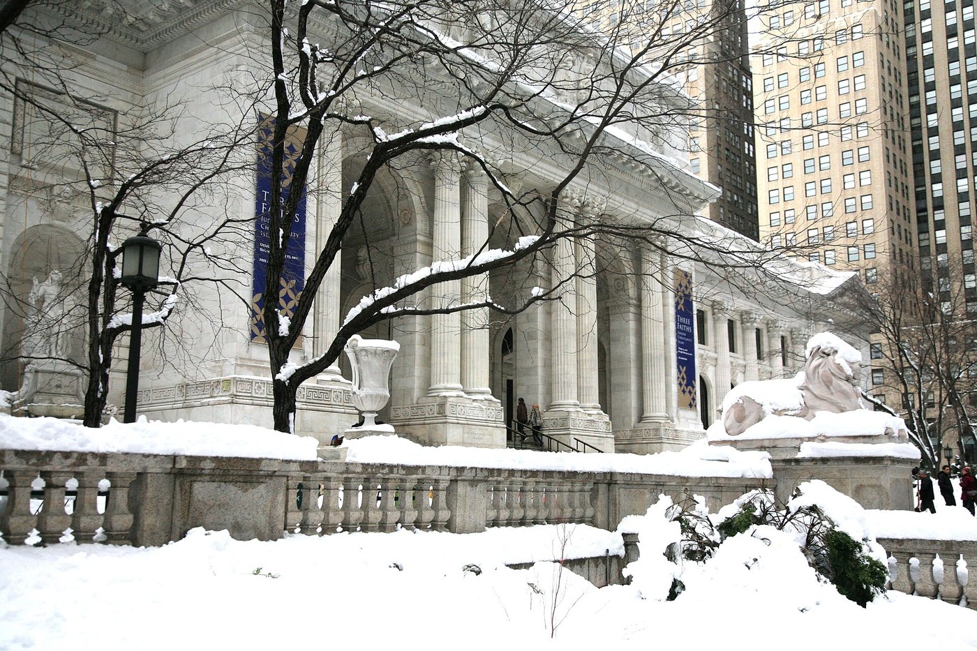 The New York Public Library's Fifth Avenue facade in snow at dusk.