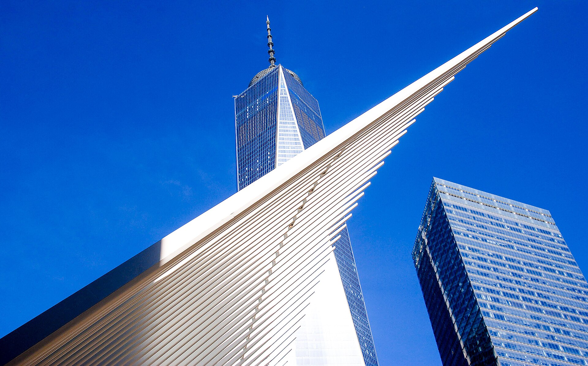 The white ribbed exterior of the Oculus at the World Trade Center, with One World Trade Center behind it