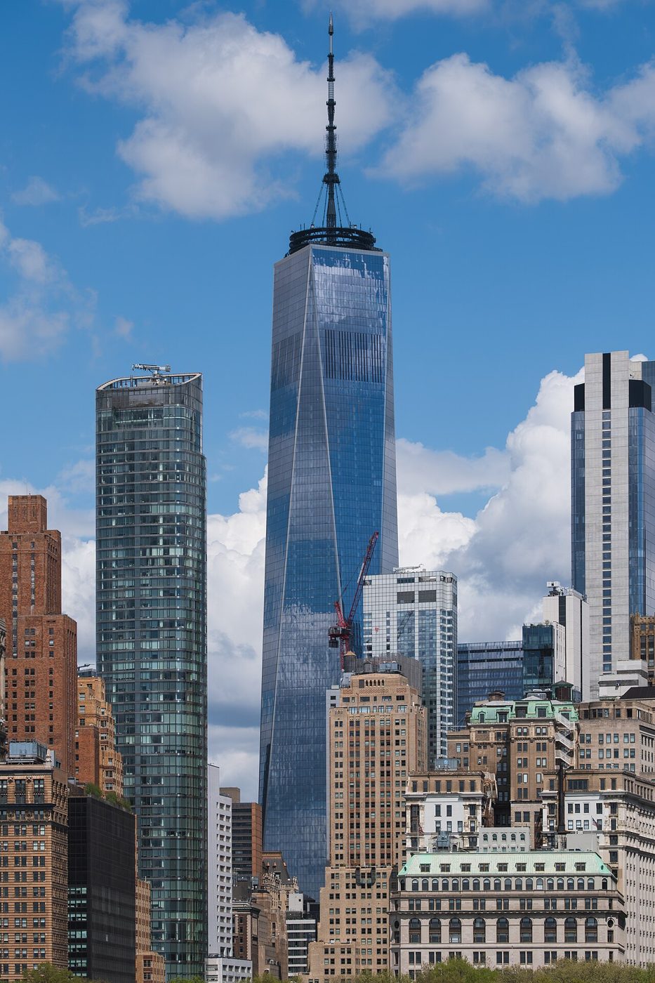 One World Trade Center, a tall glass tower with a long spire, rising above the Lower Manhattan skyline seen from New York Harbor