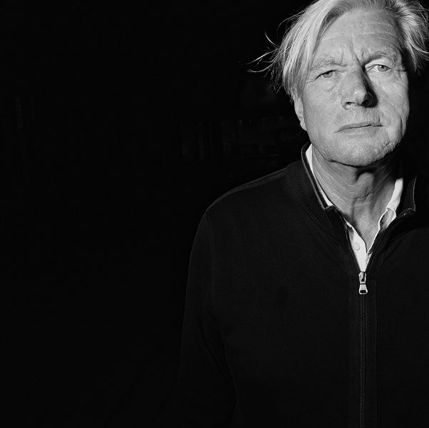 Black and white portrait of Piet Oudolf, an older man with light hair in a dark zip jacket, looking at the camera