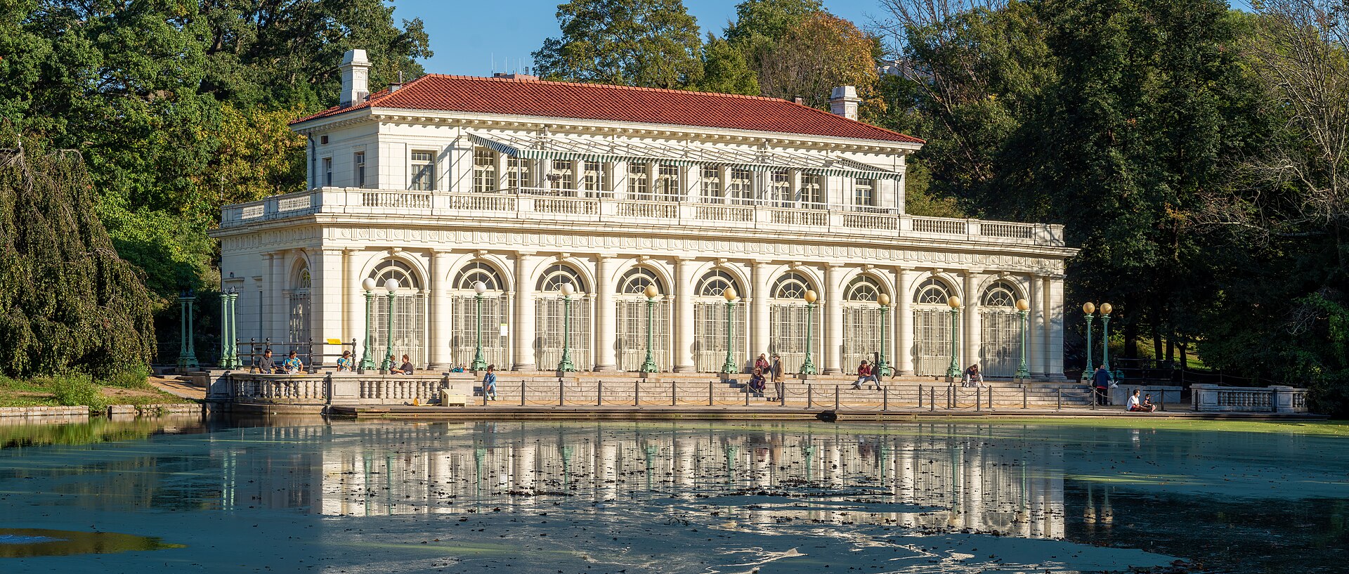 The white Boathouse with a red tile roof, reflected in the Lullwater