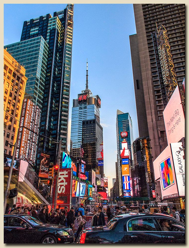 Times Square looking north from the TKTS booth, with pedestrians, billboards and towers under a blue sky