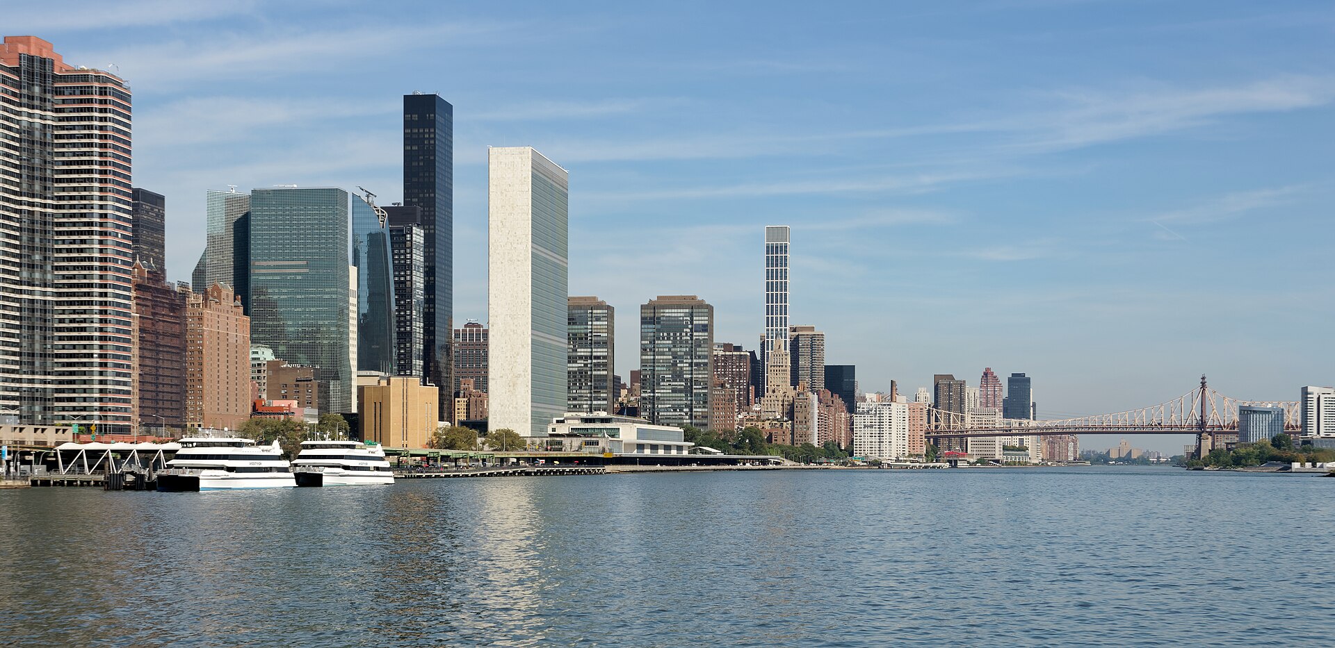 The United Nations Secretariat tower and its neighbors seen from across the East River, with the Queensboro Bridge in the distance