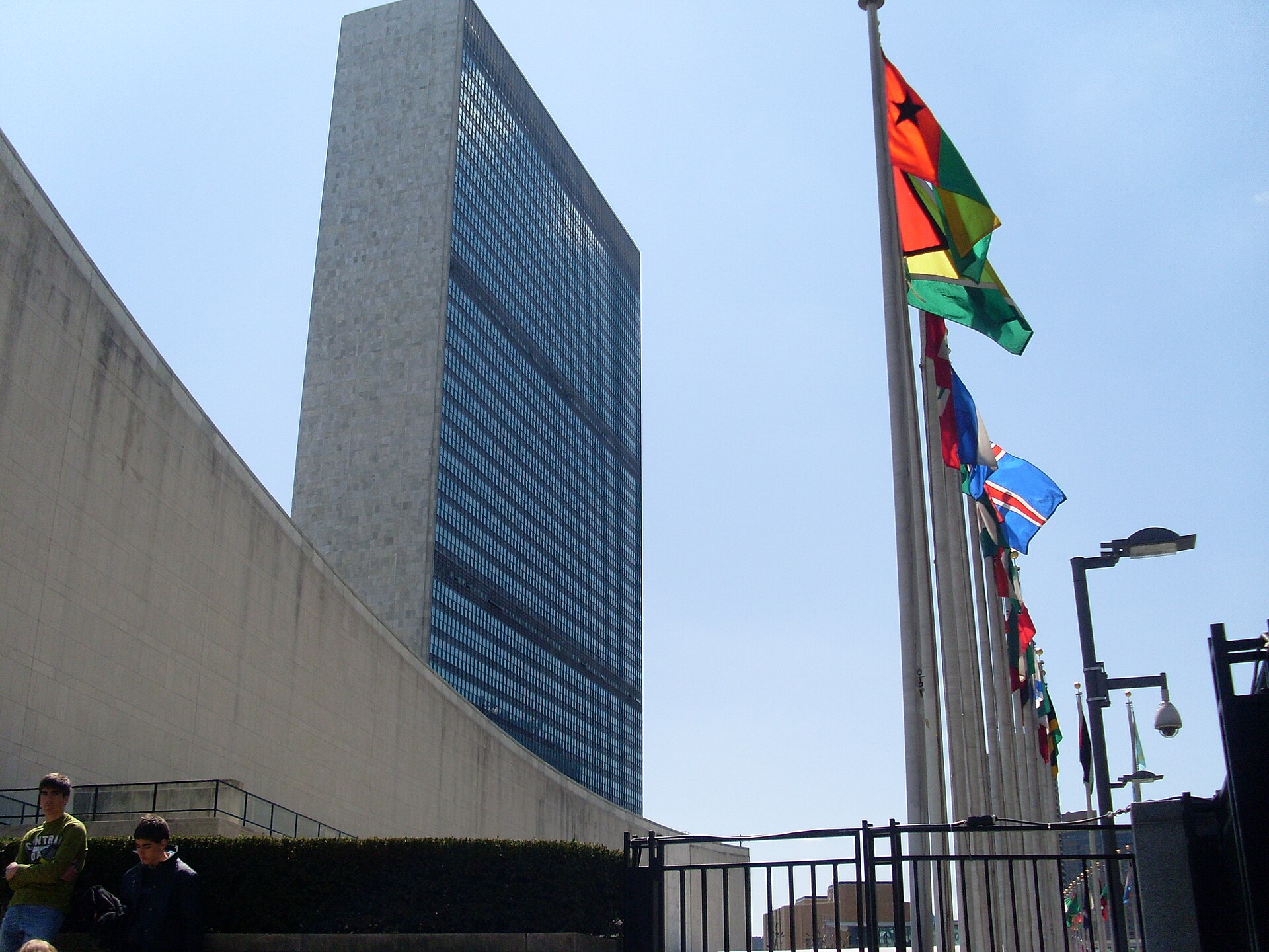 The UN Secretariat tower seen from the visitor entrance, with a row of member state flags on flagpoles