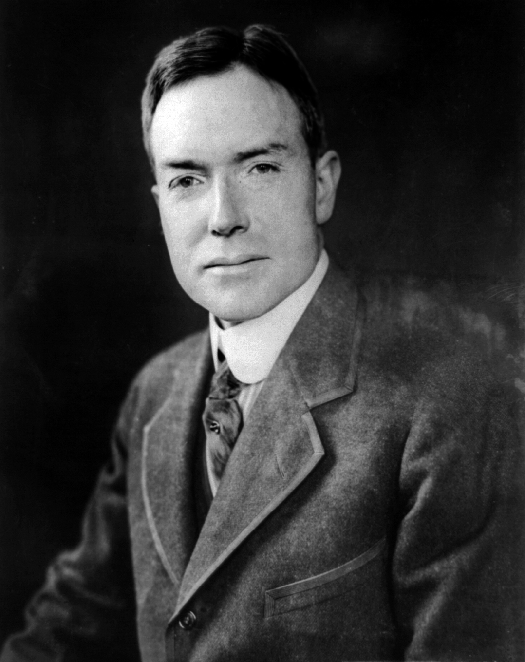A black and white portrait of John D. Rockefeller Jr. as a young man in a suit and tie