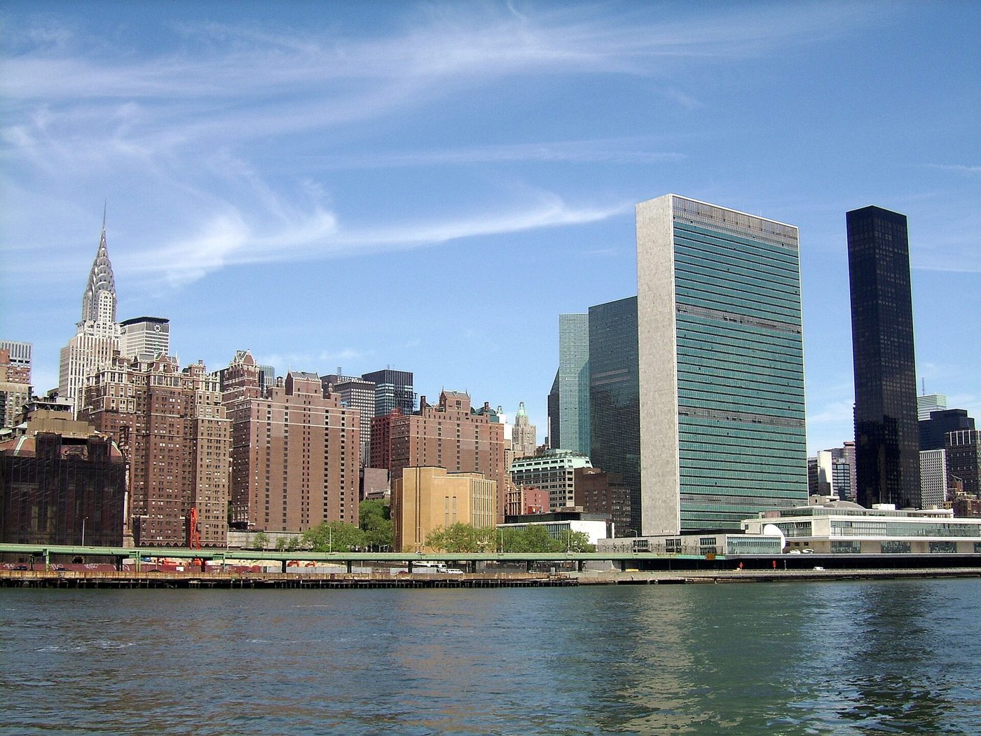 The glass slab of the United Nations Secretariat beside the dark bronze Trump World Tower, seen across the East River