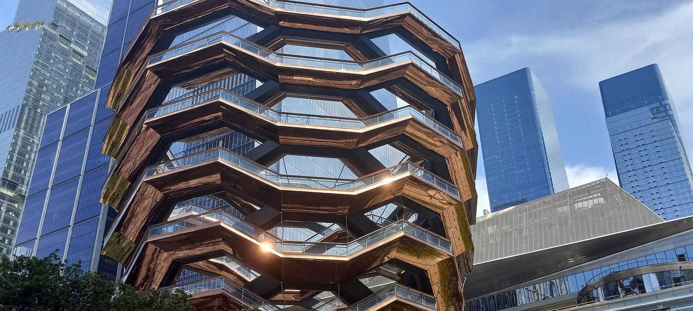 The Vessel at Hudson Yards, a honeycomb-shaped structure of copper-colored steel stairways, seen against glass towers