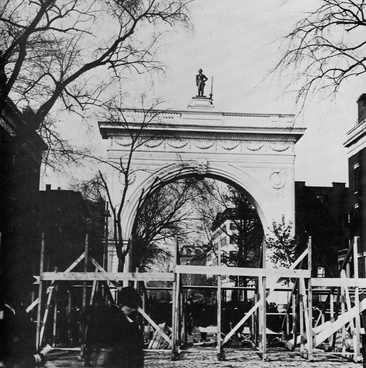 A black and white photograph of the first temporary Washington Arch in 1889, with wooden scaffolding at its base