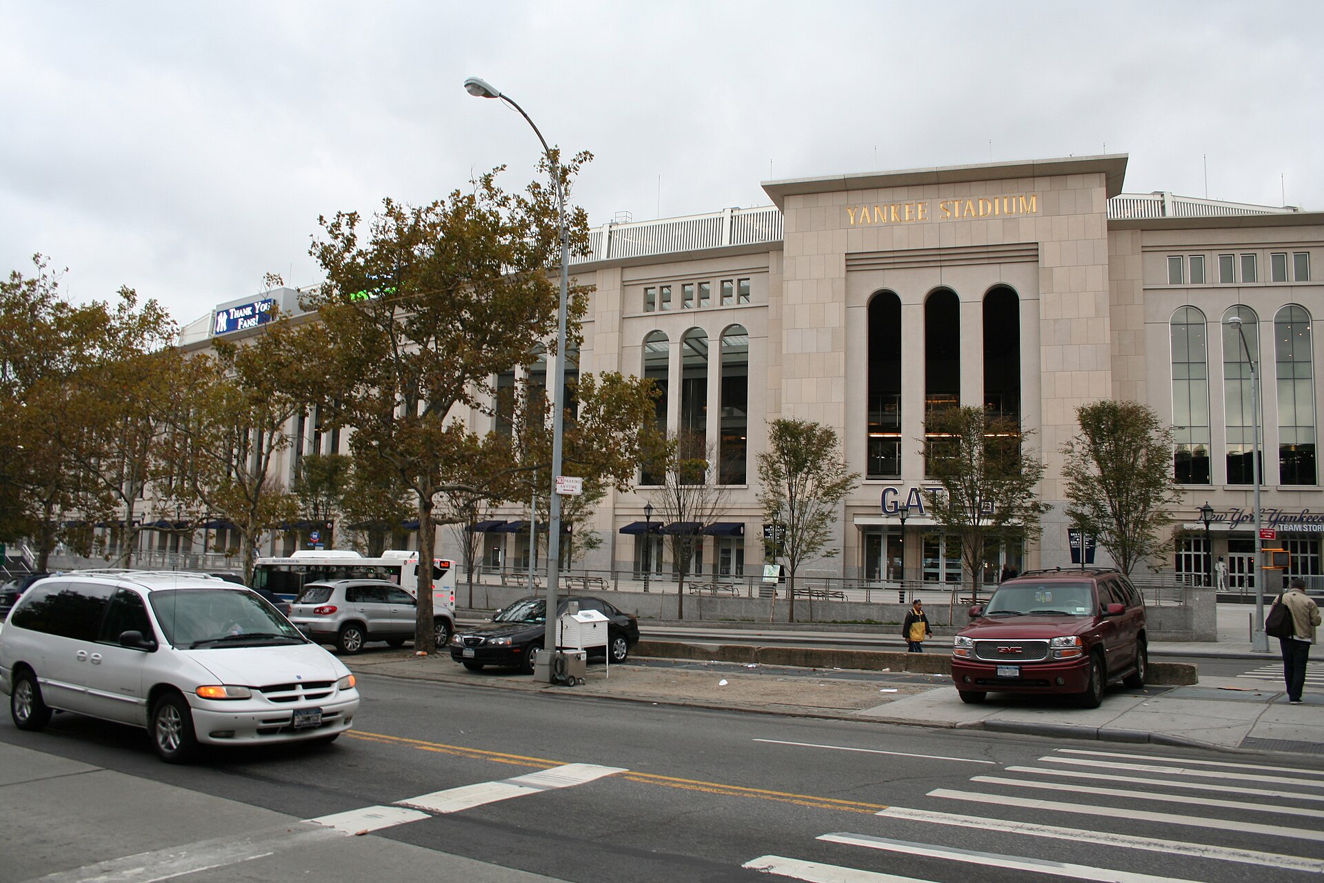 The limestone exterior of the current Yankee Stadium from East 161st Street in its first season, with YANKEE STADIUM lettered in gold over the gate