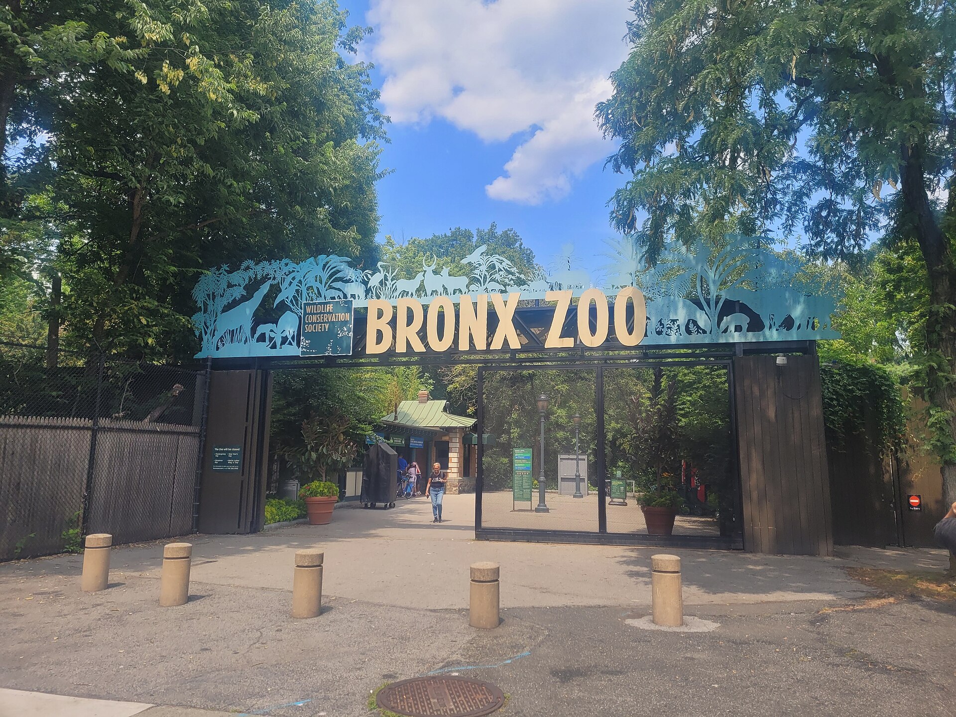 The Bronx Zoo's Asia Gate entrance, a tall gate topped with the words Bronx Zoo and animal silhouettes, on a summer day